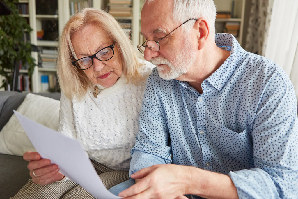 Senioren Paar liest einen Vertrag oder eine Vorsorgevollmacht oder eine Patientenverfügung